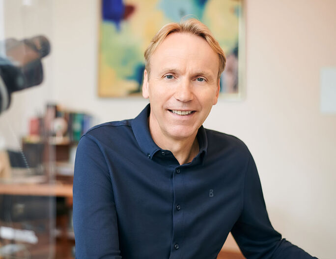Prof. Dr. med. Philipp Jacobi sitzt im Beratungszimmer und lächelt freundlich